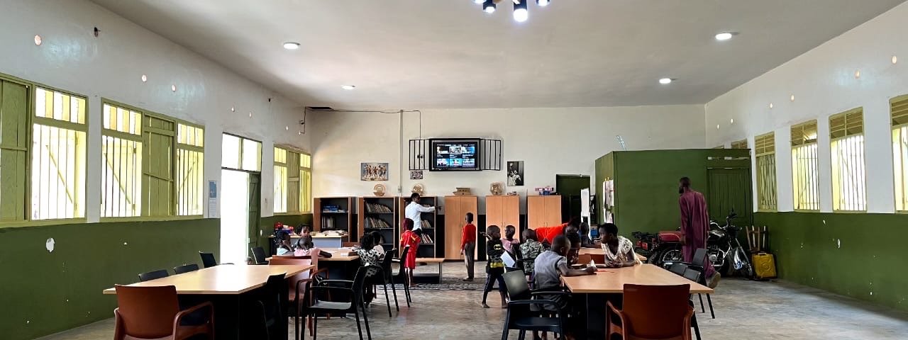 The wide hall of KPDDI's community centre in Kireka, with children reading at tables