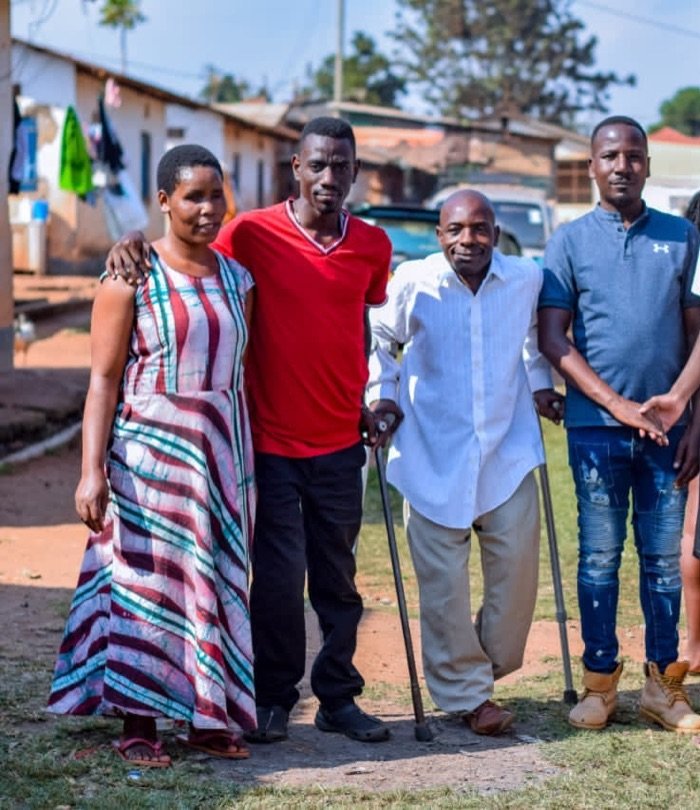 Four KPDDI members standing arm in arm outdoors in Kireka, one using crutches
