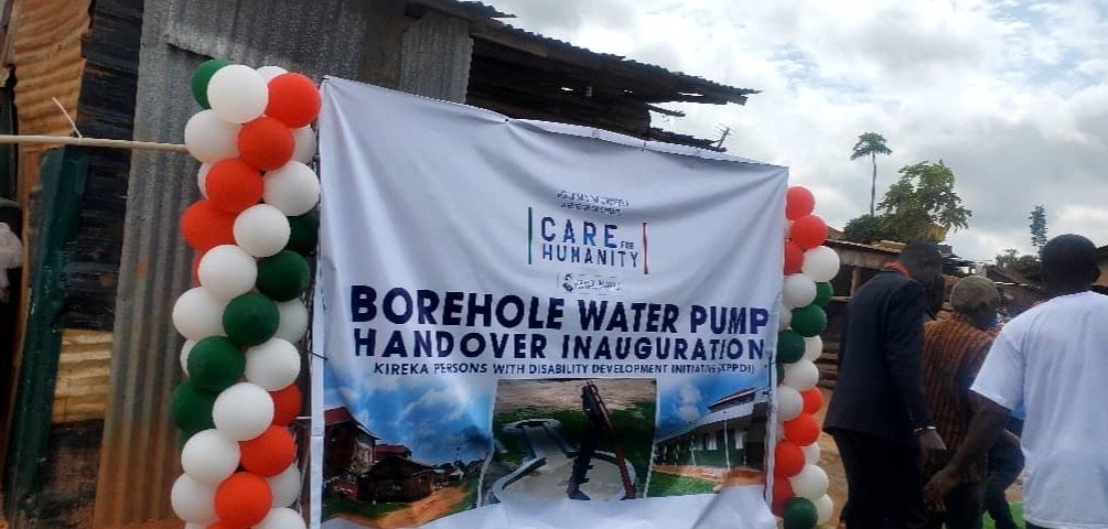 A printed KPDDI event banner framed by green, white and orange balloons outside the compound in Kireka