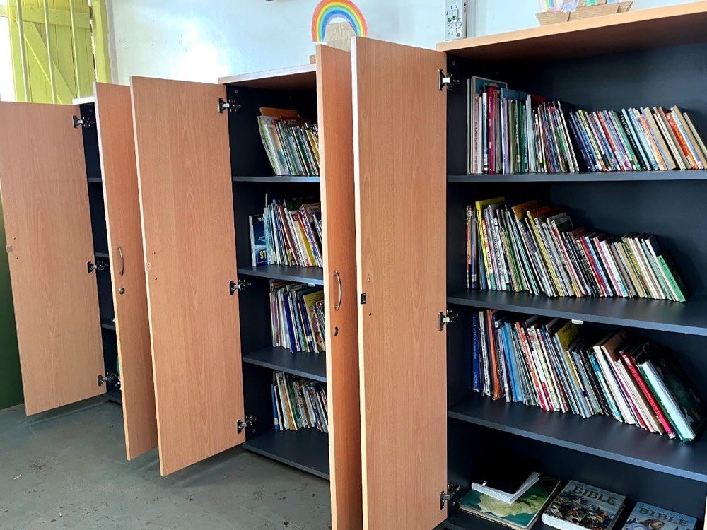 Wooden cabinets filled with children's books in KPDDI's reading room