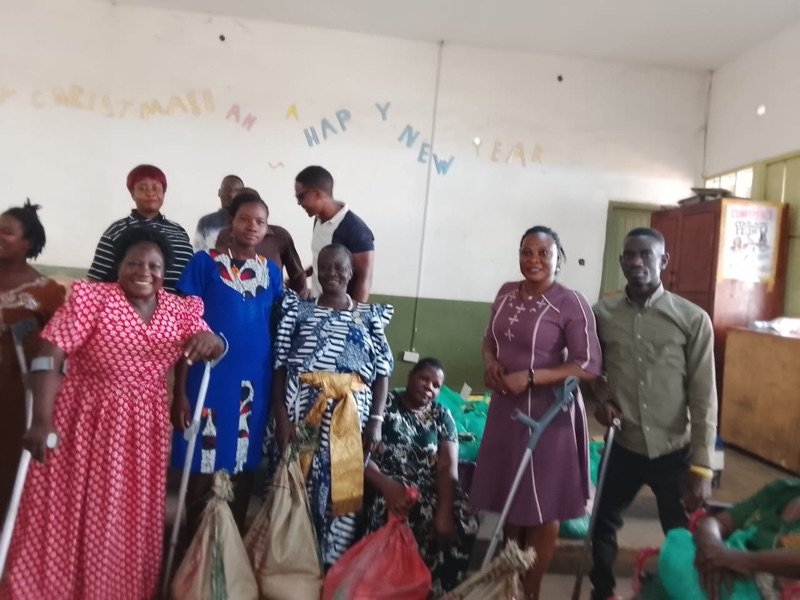 KPDDI members, several using crutches, standing in the hall with sacks of food ready for distribution